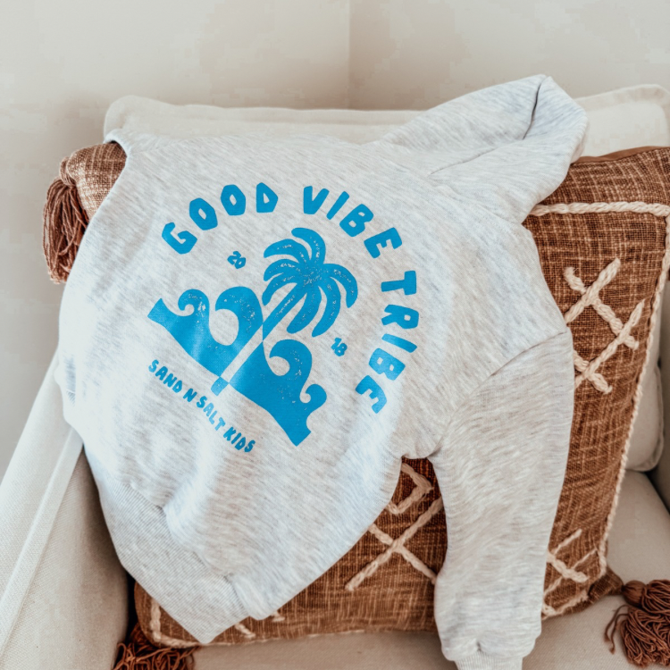 Grey marle kids hoodie with bright blue “Good Vibe Tribe” print. Soft, sustainable winter jumper designed for beach days and skatepark hangs.