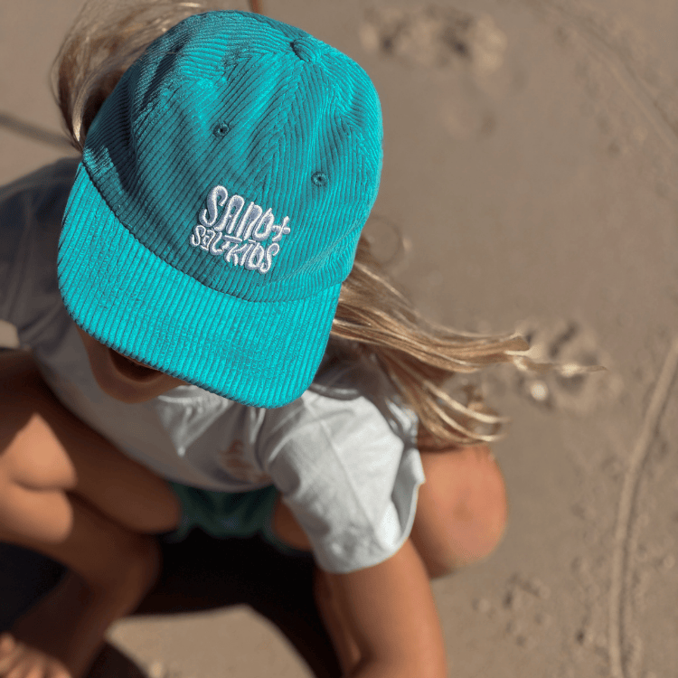 Child wearing cord cap with Sand n Salt logo. Adjustable kids surf hat for beach days