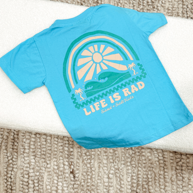 Sea blue kids t-shirt with Life Is Rad graphic, styled for beach and skate lifestyle