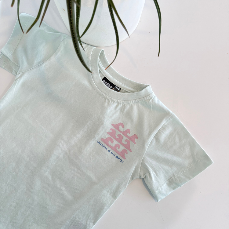 flatlay Boy blue mist Like Waves tee near the ocean. Handmade kids surf shirt for boys and girls.