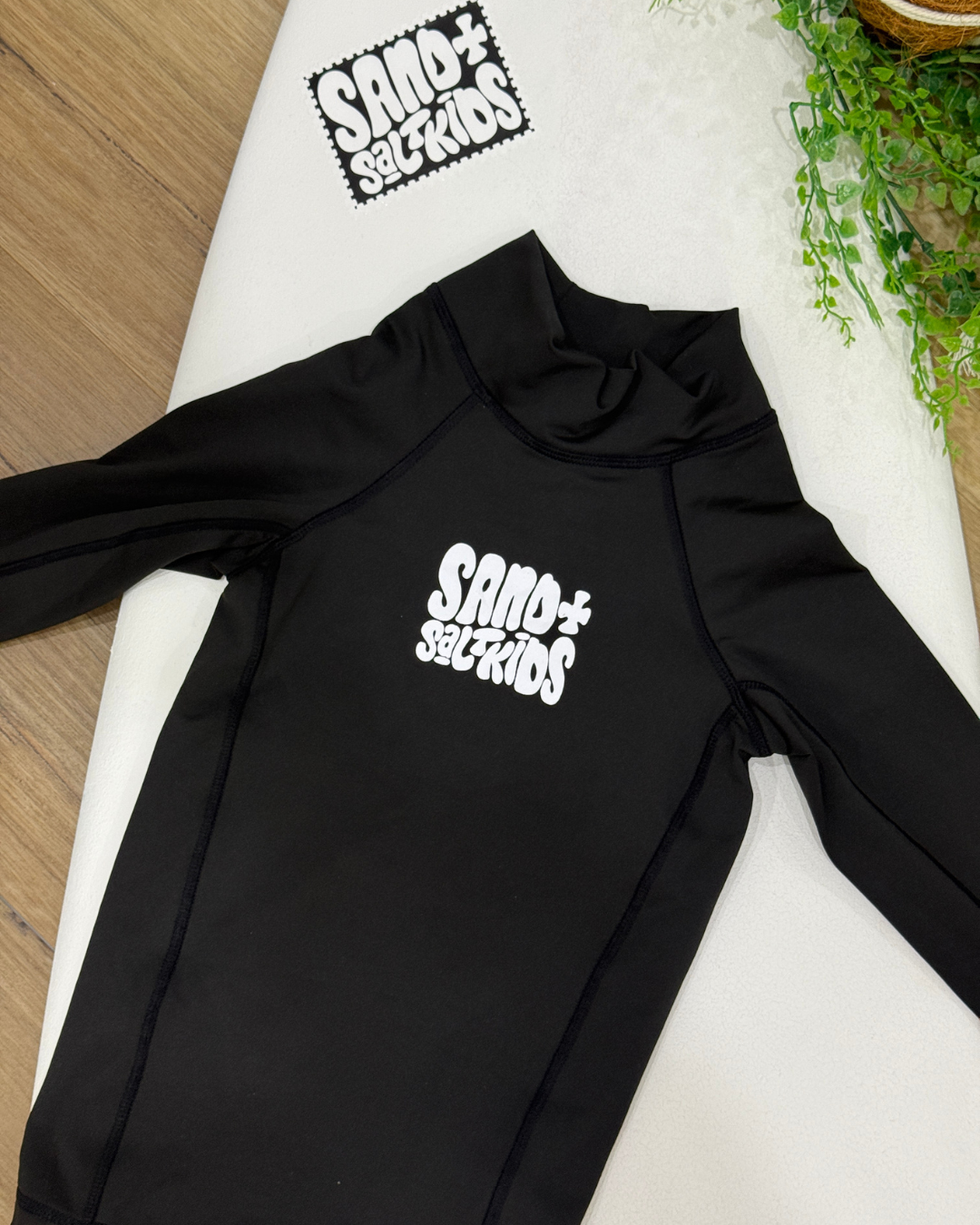 Black kids long sleeve rash vest with white Sand + Salt Kids chest logo 