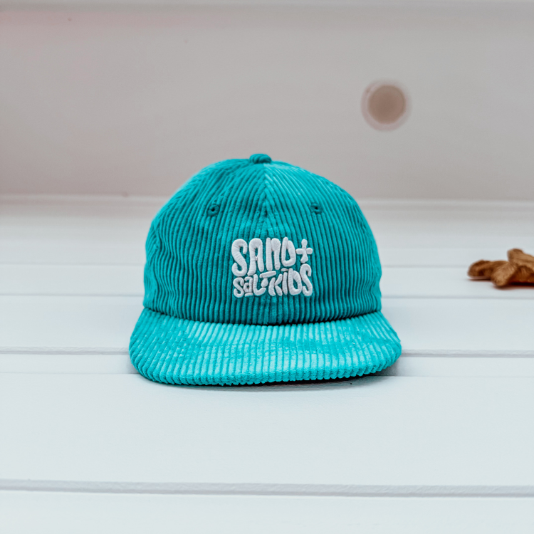 Child wearing cord cap with Sand n Salt logo. Adjustable kids surf hat for beach days