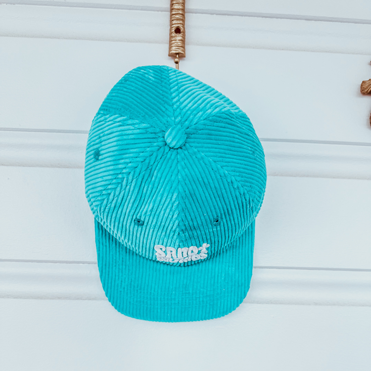 Child wearing tan cord cap with Sand n Salt logo. Adjustable kids surf hat for beach days