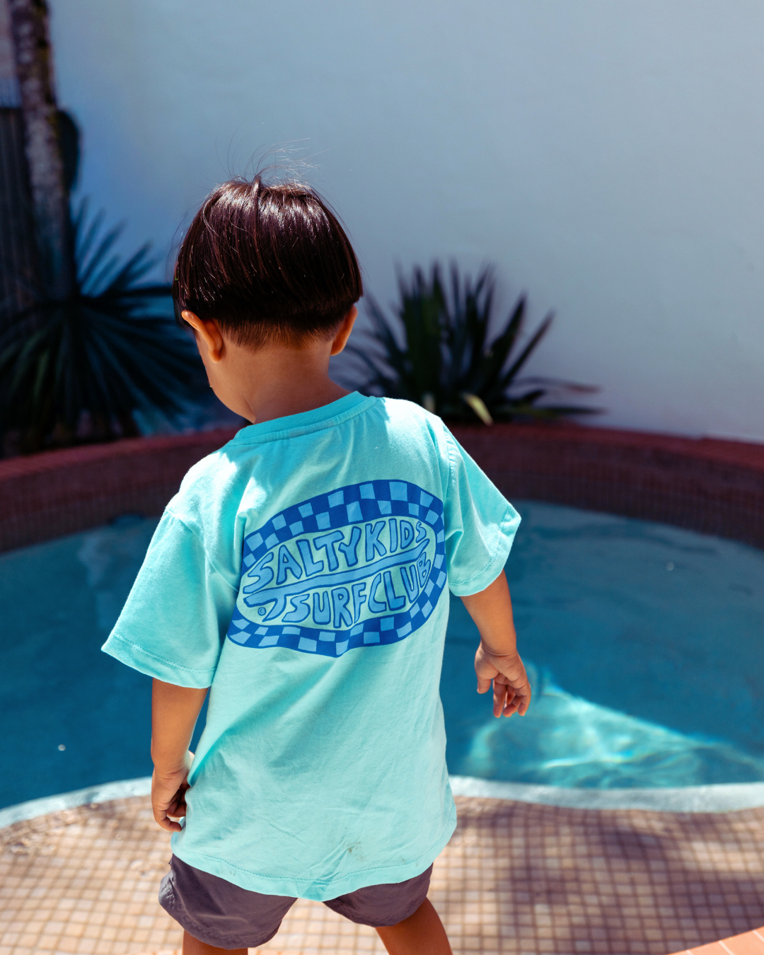 Child wearing Sand and Salt Kids Salty Kids Surf Club t-shirt poolside, relaxed fit kids surf tee designed for beach days and outdoor play